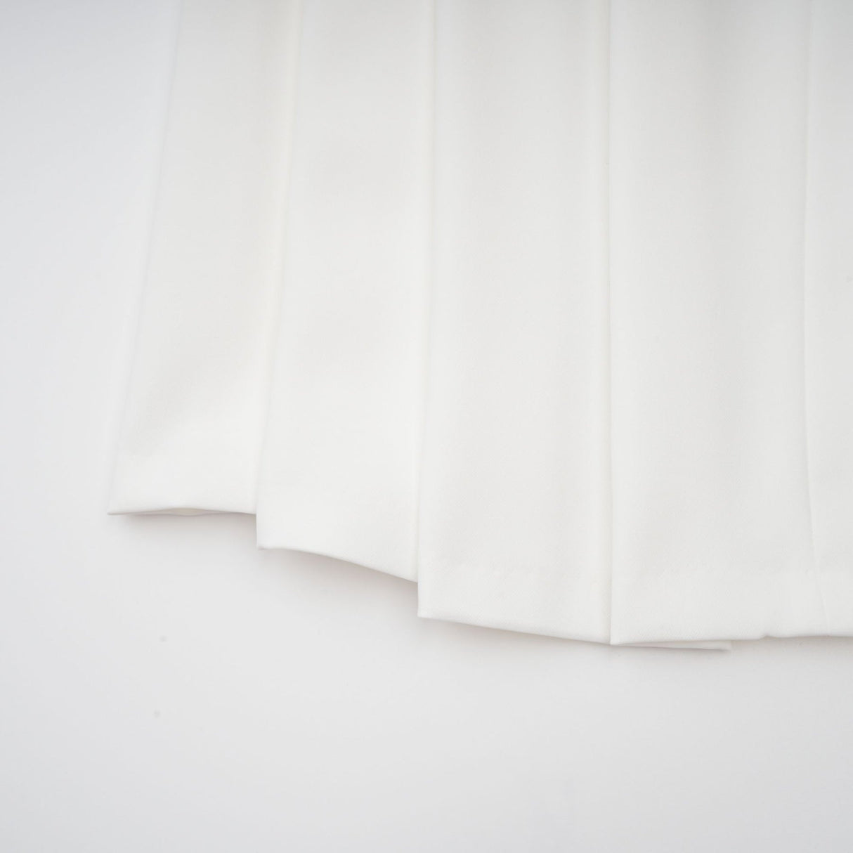 A white matching set featuring a creased top and trousers worn by a model against a plain background