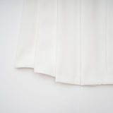 A white matching set featuring a creased top and trousers worn by a model against a plain background
