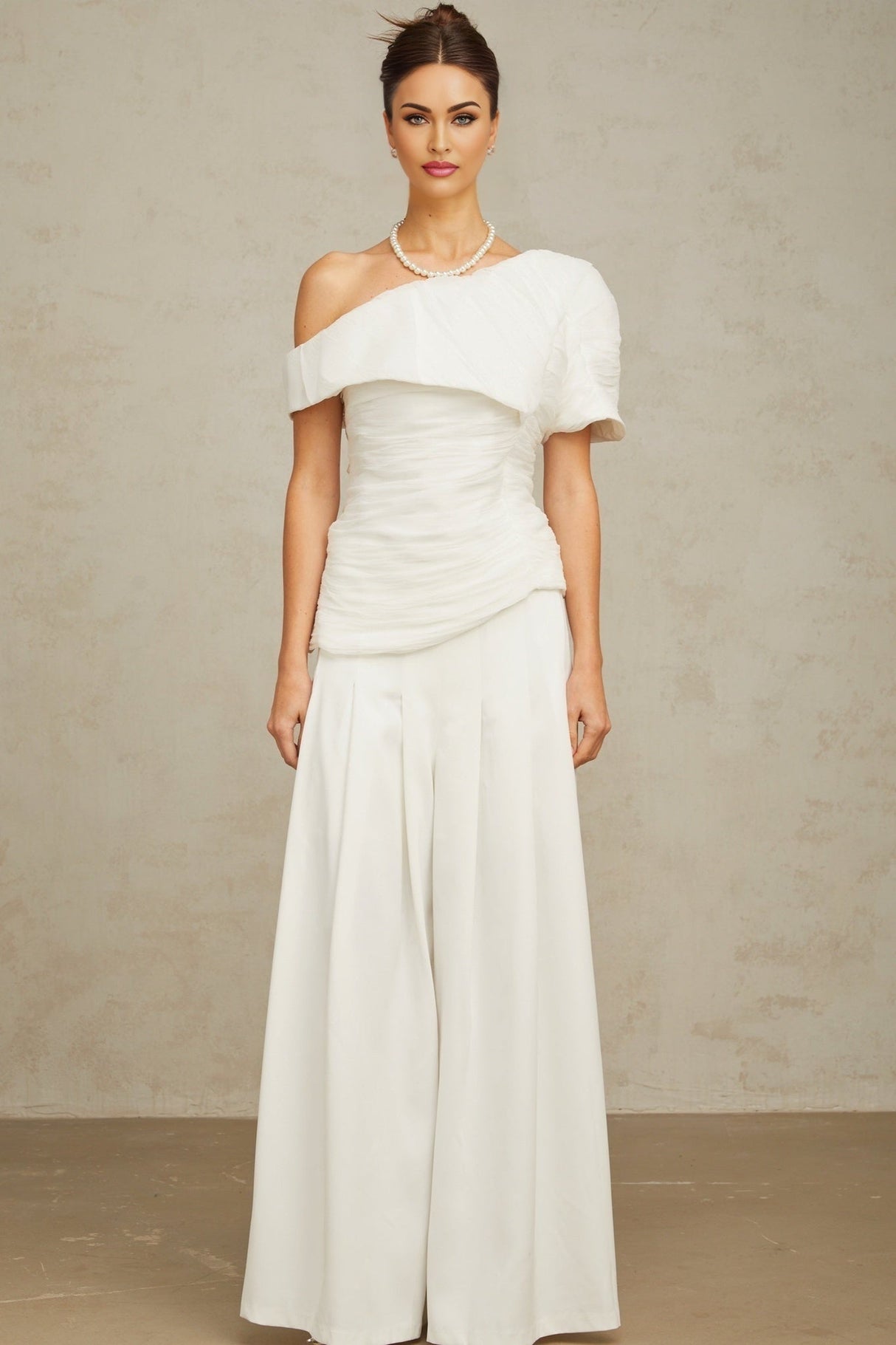 A white matching set featuring a creased top and trousers worn by a model against a plain background