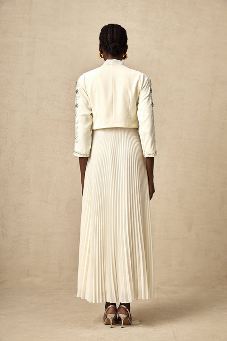 A white matching set featuring a pleated jacket and dress with embellished details The jacket has a structured silhouette while the dress is fitted Both pieces are adorned with delicate embellishments for an elegant look