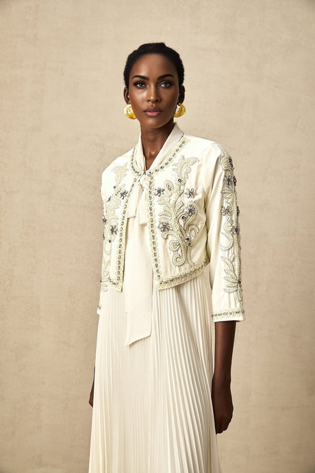 A white matching set featuring a pleated jacket and dress with embellishments The jacket has a fitted silhouette and the dress is sleeveless Both pieces are adorned with delicate embellishments creating an elegant and coordinated look