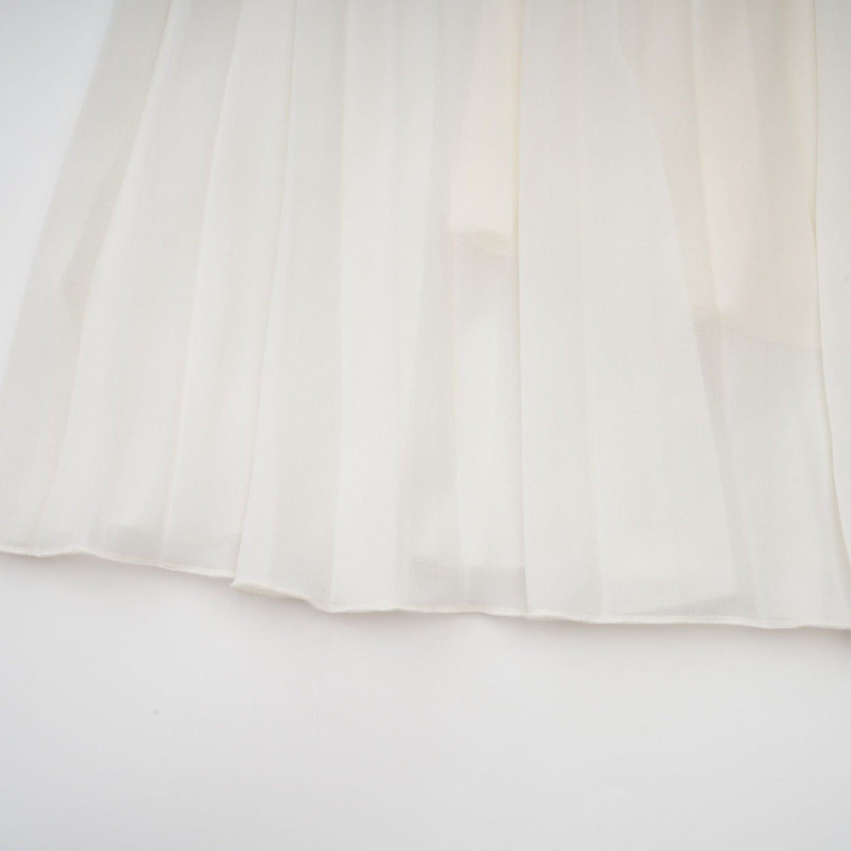 A white matching set featuring a pleated jacket and dress with embellishments The jacket has long sleeves and the dress has a fitted silhouette Both pieces are adorned with delicate embroidery or beadwork creating an elegant ensemble