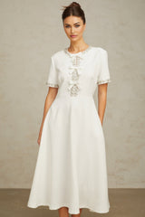 A white midi dress featuring a crystalaccented bow detail and a fitted silhouette named Cassiopeia