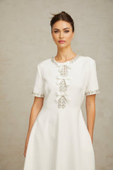 A white midi dress featuring crystal accents and a bow detail showcasing the Cassiopeia design
