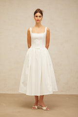 A white midi dress with a bowknot detail and flounced design featuring a feminine silhouette and delicate ruffles