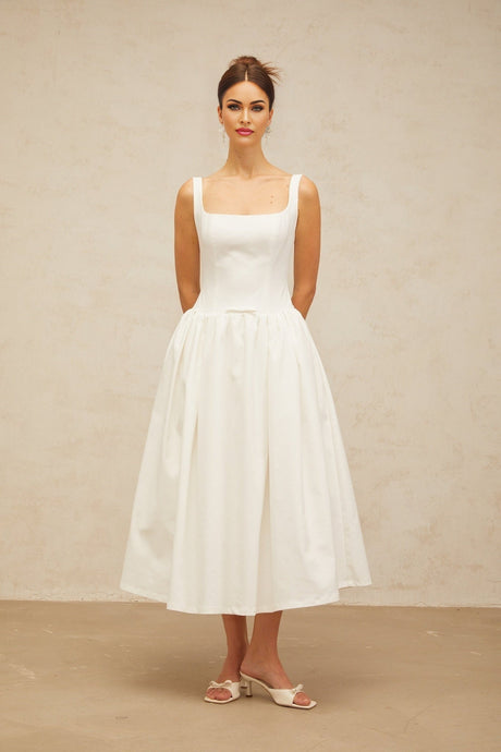 A white midi dress with a bowknot detail and flounced design featuring a feminine silhouette and delicate ruffles