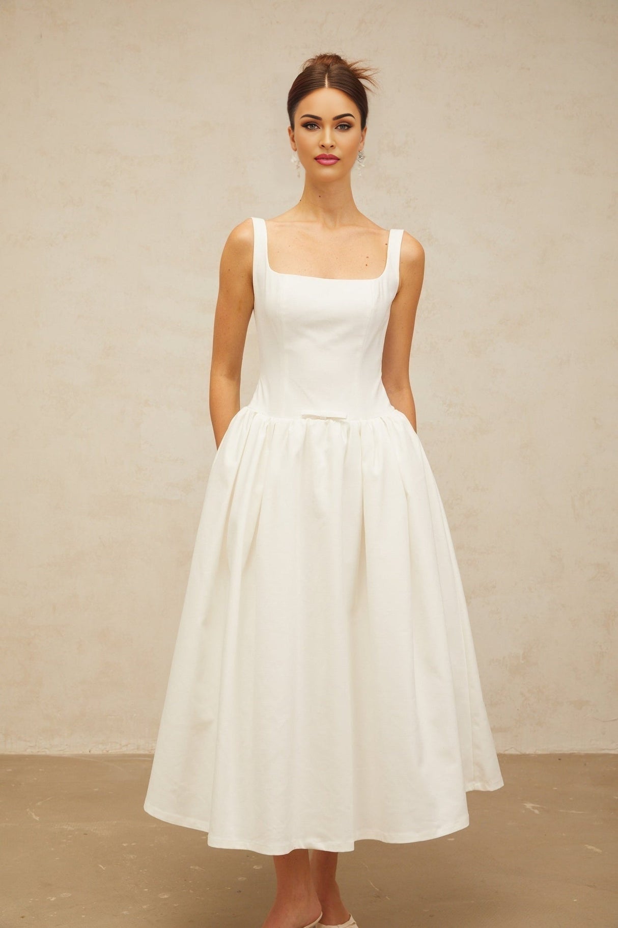A white midi dress with a bowknot detail and flounced hem featuring a feminine silhouette and delicate design elements
