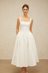 A white midi dress with a bowknot detail and flounced hem featuring a feminine silhouette and delicate design elements