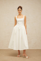 A white midi dress with a bowknot detail and flounced hemline featuring a feminine and elegant design