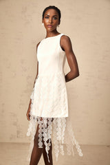 A white midi dress with a discshaped design and fringe details modeled by a woman named Justine