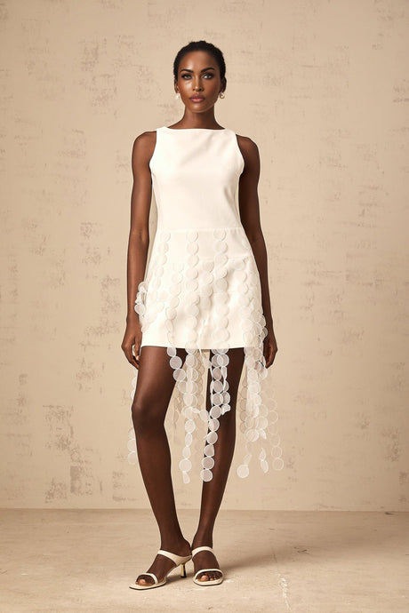 A white midi dress with a discshaped design pattern and fringe details worn by a model named Justine