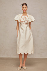 A white midi dress with a floral jacquard pattern featuring a fitted bodice and flared skirt