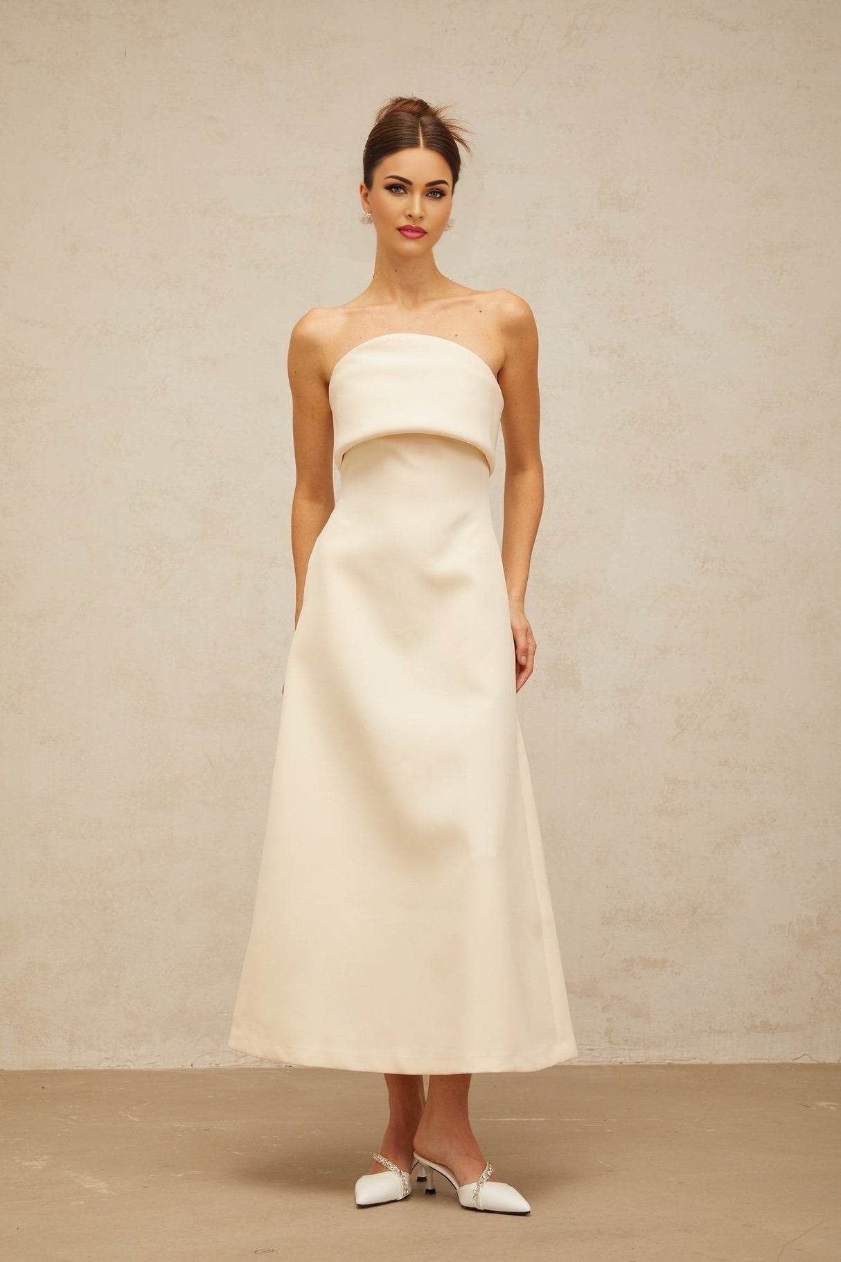 A white midi dress with a folded corset style bodice and a fitted silhouette named Raphaelle