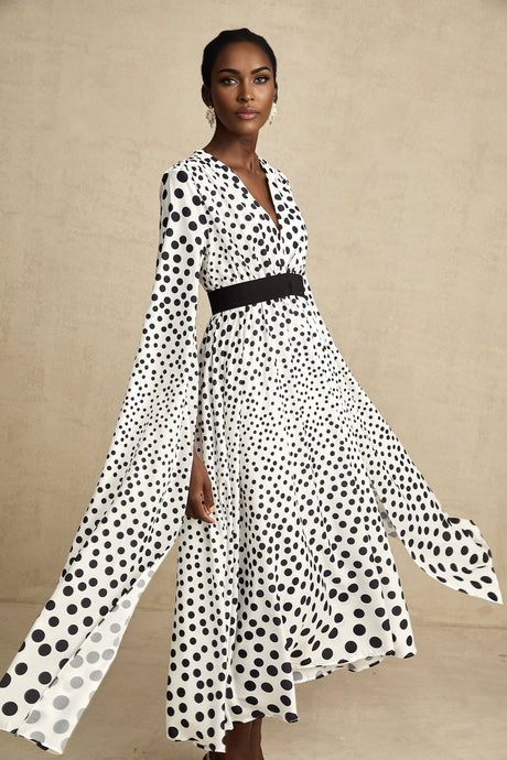 A white midi dress with black polka dots featuring slit sleeves and a fitted silhouette on a female model