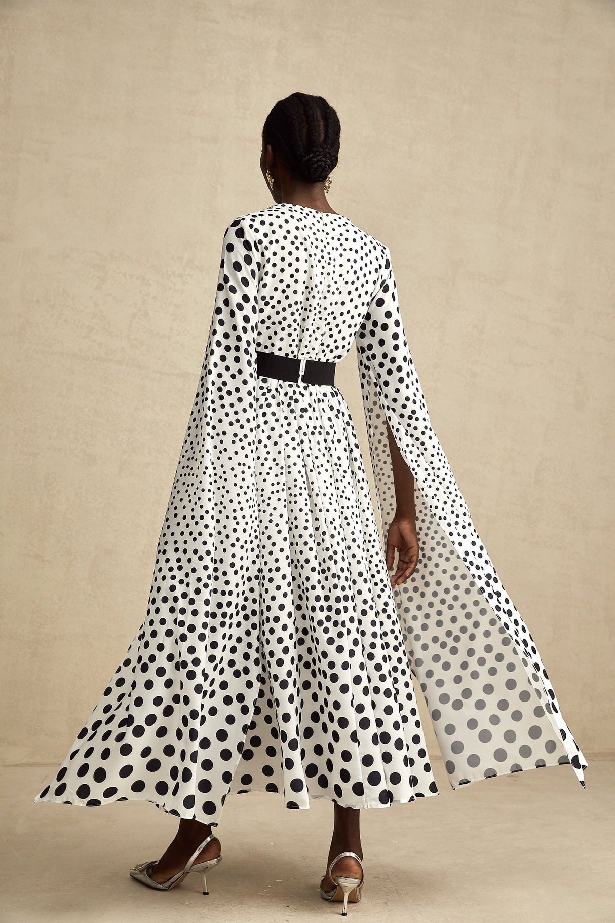 A white midi dress with black polka dots featuring slit sleeves and a fitted silhouette