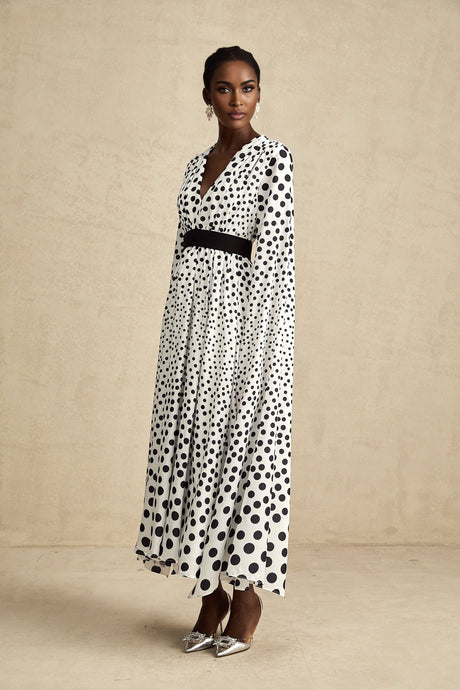 A white midi dress with black polka dots featuring slit sleeves and a fitted silhouette