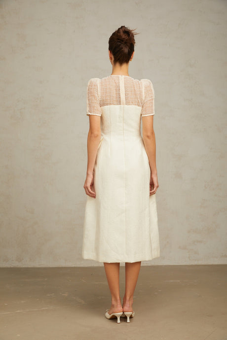 A white midi dress with braided panelling and a fitted silhouette featuring a round neckline and sleeveless design