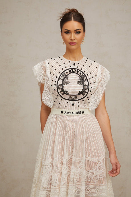 A white midi dress with jacquard floral lace pattern featuring pleated design and named Phoebe