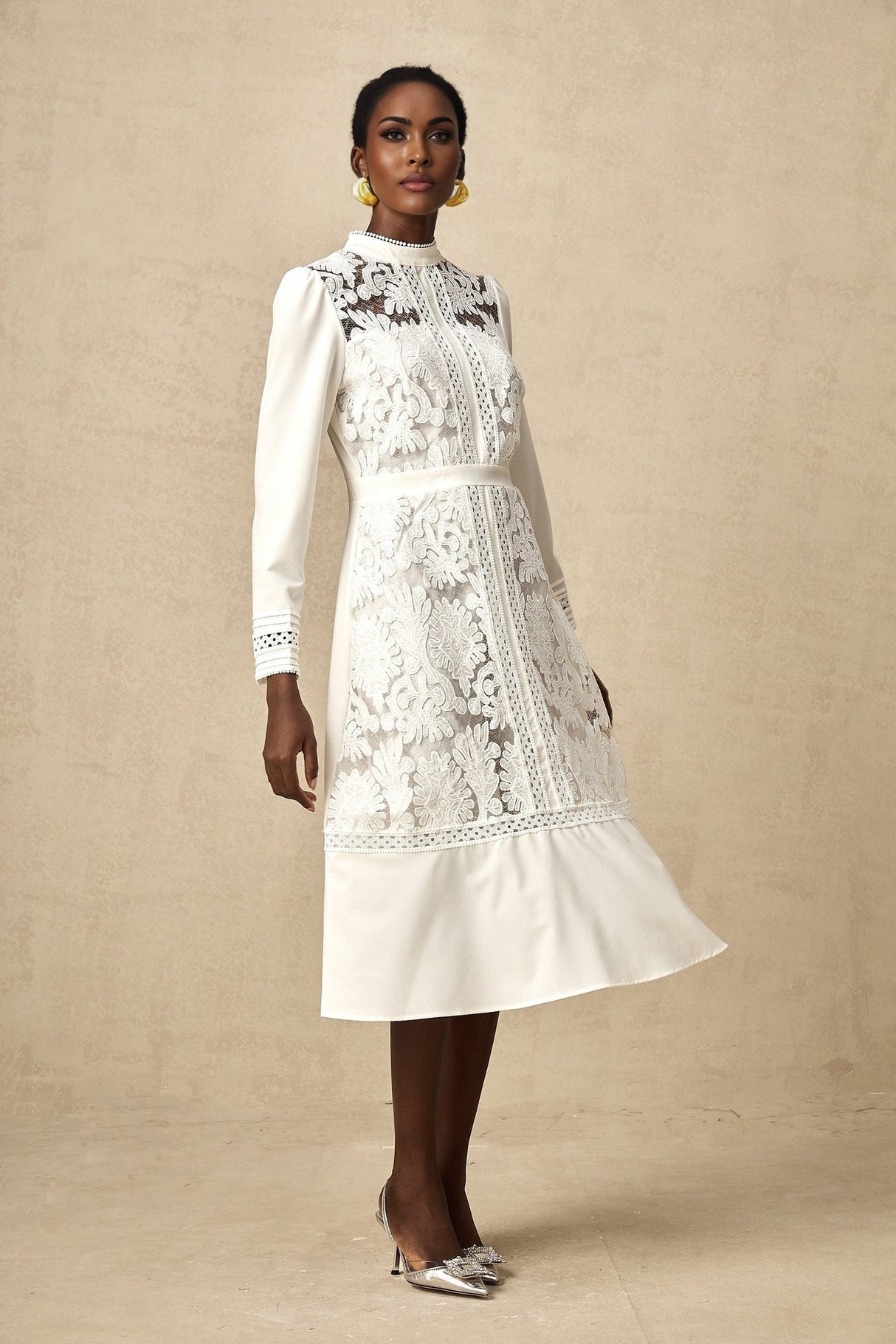 A white midi dress with panelled design and embroidery details named Madeleine featuring a feminine silhouette and intricate stitching throughout the fabric