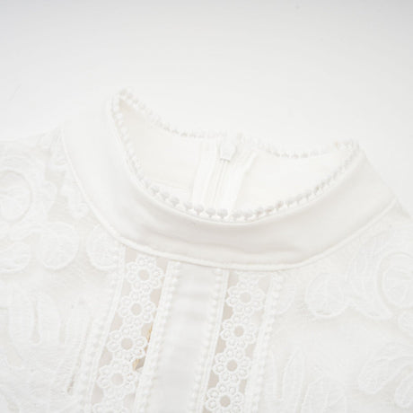 A white midi dress with panelled design and embroidery details named Madeleine featuring a fitted silhouette and delicate floral patterns