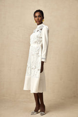 A white midi dress with panelled design and embroidery details named Madeleine featuring a flowy silhouette and delicate stitching patterns