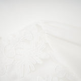 A white midi dress with panelled design and embroidery details named Madeleine featuring a flowy silhouette and delicate stitching throughout