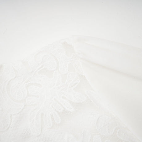 A white midi dress with panelled design and embroidery details named Madeleine featuring a flowy silhouette and delicate stitching throughout