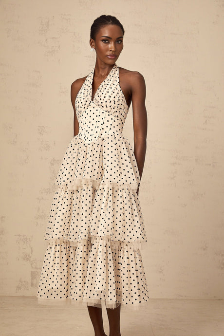 A white midi dress with small ivory polka dots featuring a tiered skirt and sleeveless design