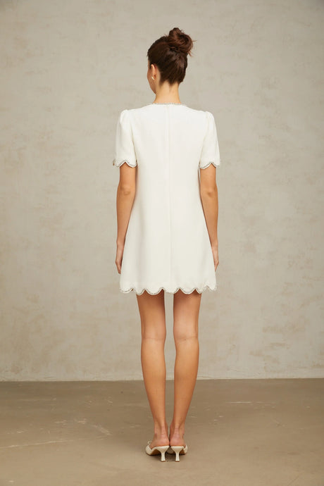 A white mini dress adorned with crystal embellishments featuring a short hemline and sleek design named Berenice