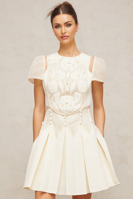 A white mini dress featuring delicate flower embroidery details throughout the fabric