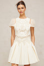 A white mini dress featuring delicate flower embroidery details throughout the fabric