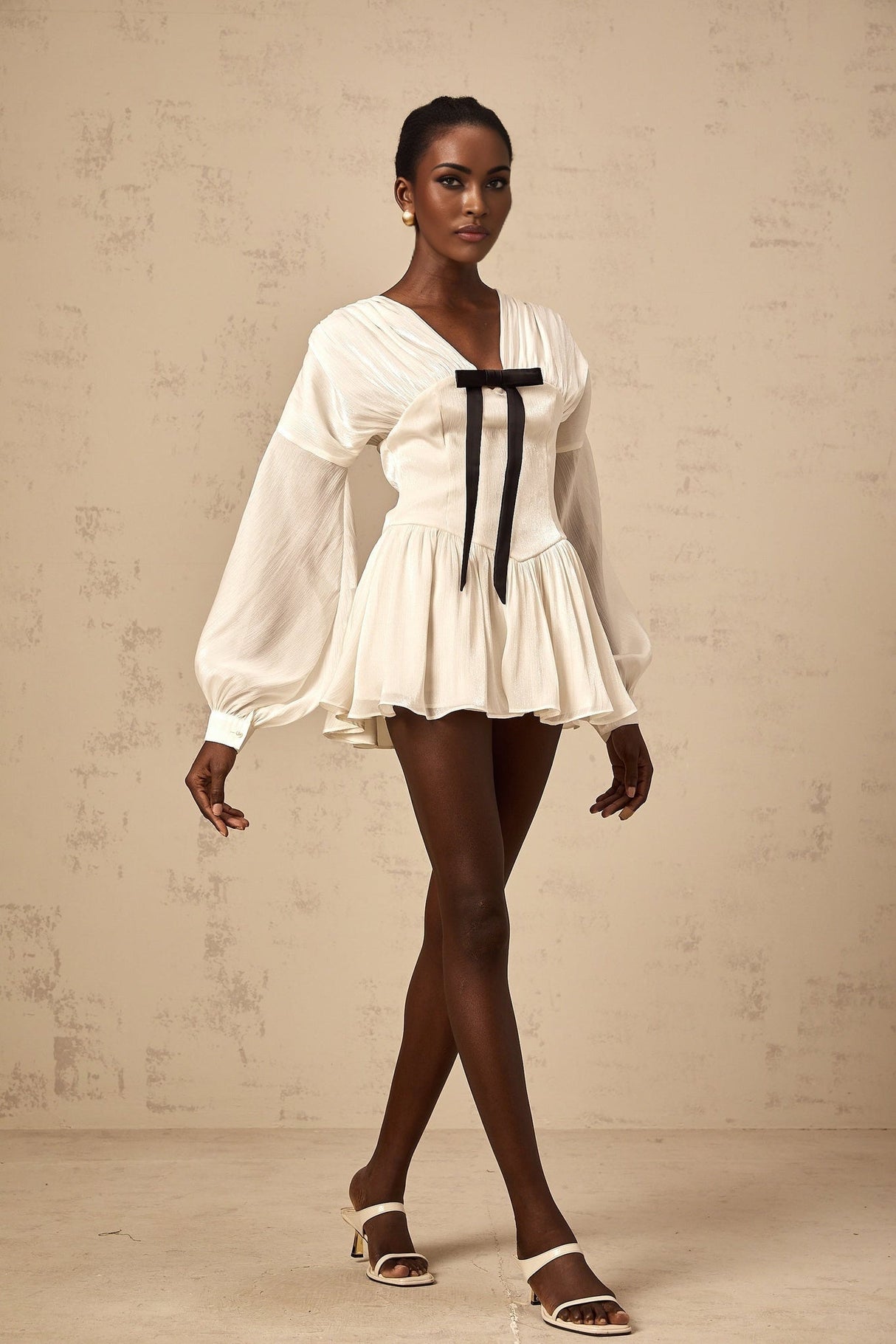 A white mini dress with a bowknot detail and glitter accents named Lina