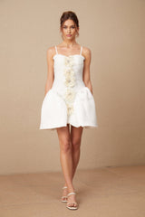 A white mini dress with a bustier top featuring a delicate flower pattern throughout the fabric