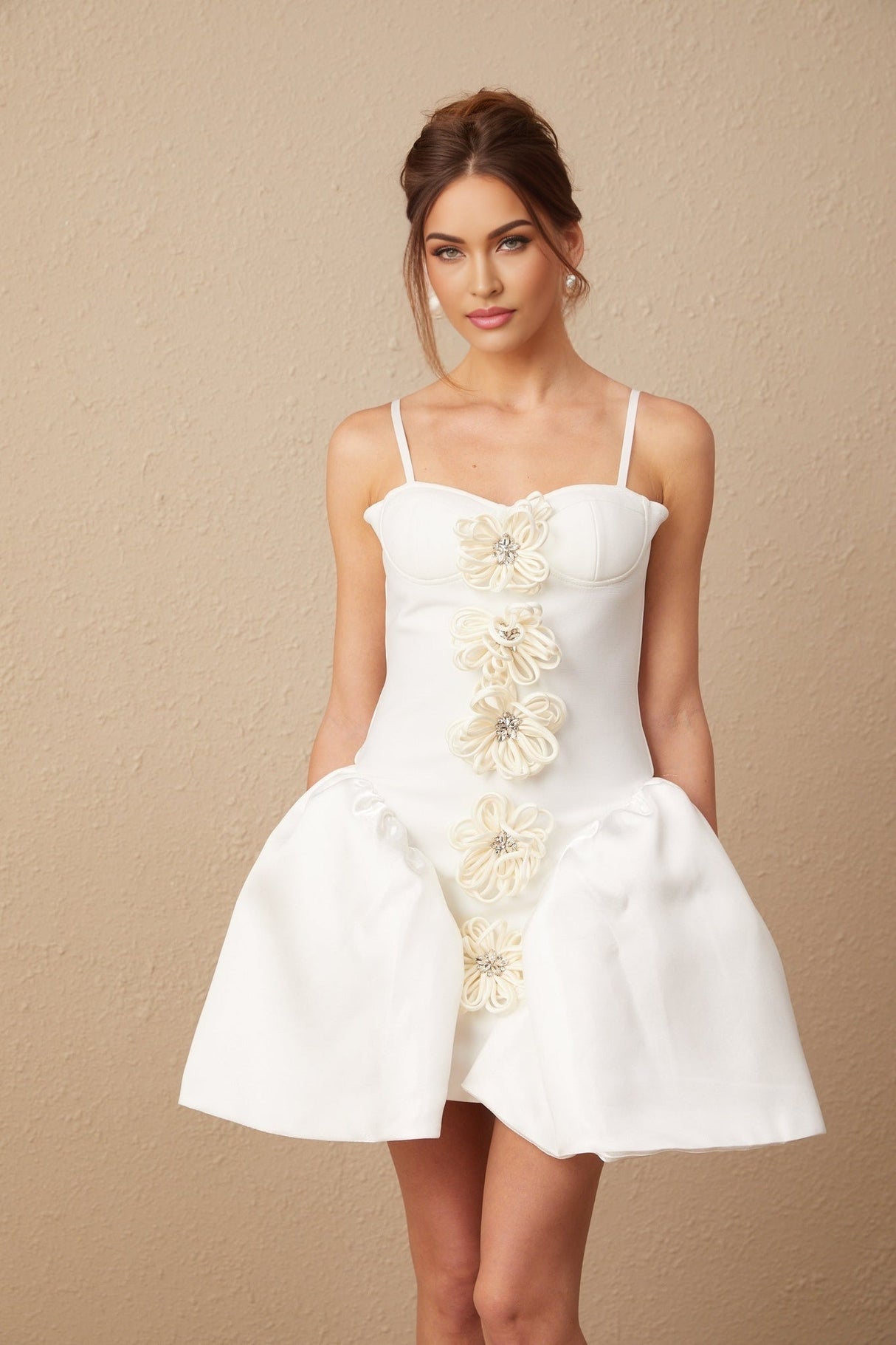A white mini dress with a bustier top featuring a floral motif pattern throughout the fabric