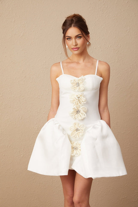 A white mini dress with a bustier top featuring a floral motif pattern throughout the fabric