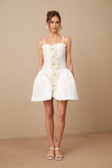 A white mini dress with a bustier top featuring a floral pattern throughout the fabric The dress has a fitted silhouette and ends above the knee