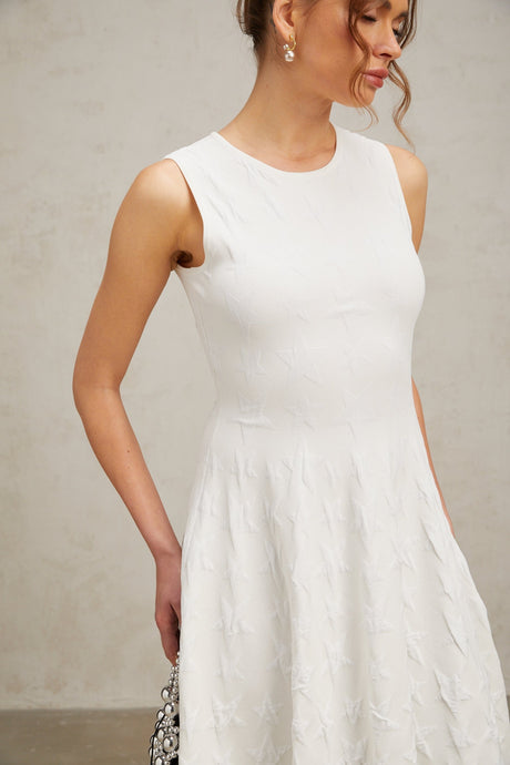 A white mini dress with a star pattern knitted into the fabric featuring a jasmine design