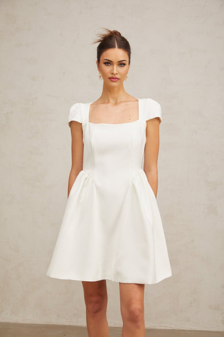 A white mini dress with cap sleeves featuring a fitted bodice and flared skirt likely made of lightweight fabric suitable for warm weather or casual occasions