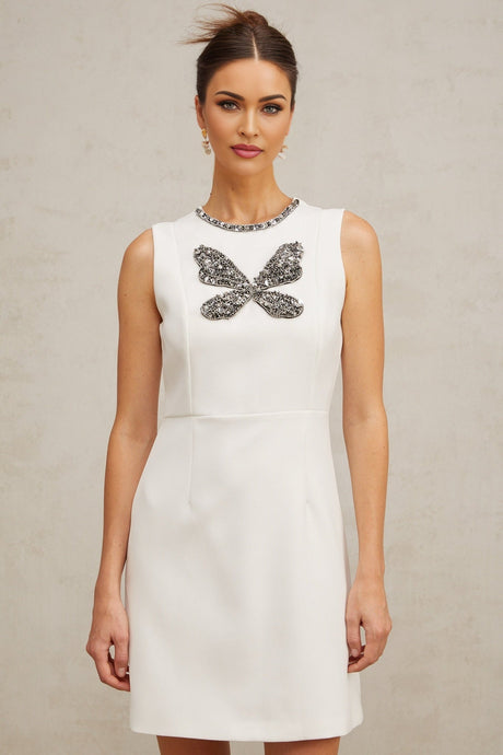 A white mini dress with crystal butterfly embellishments on a model against a plain background