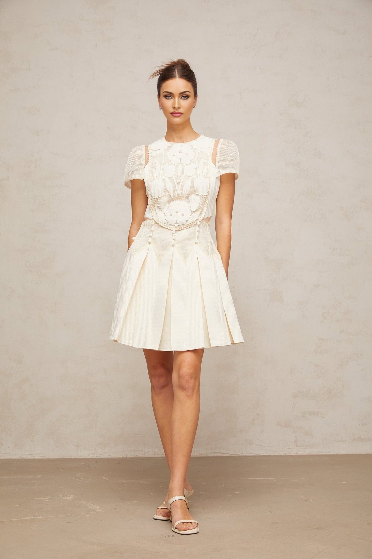 A white mini dress with delicate flower embroidery details covering the fabric Maelle brand