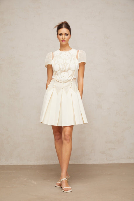 A white mini dress with delicate flower embroidery details covering the fabric Maelle brand