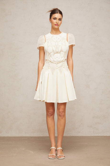 A white mini dress with delicate flower embroidery pattern adorning the fabric