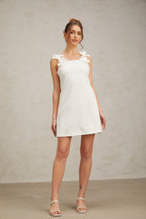 A white mini dress with faux flower embellishments and a short hemline