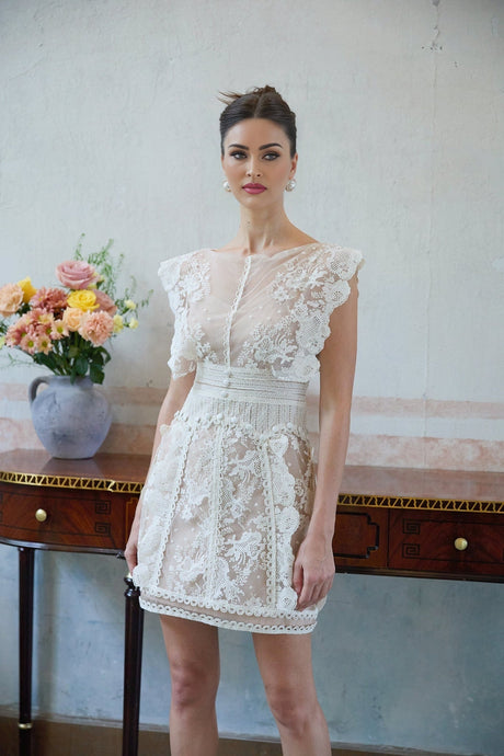 A white mini dress with floral embroidery and lace detailing featuring a delicate and feminine design
