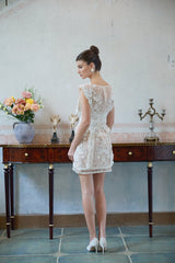 A white mini dress with floral embroidery and lace detailing featuring a short hemline and delicate feminine design
