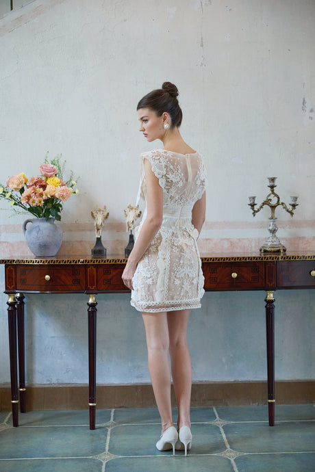 A white mini dress with floral embroidery and lace detailing featuring a short hemline and delicate feminine design