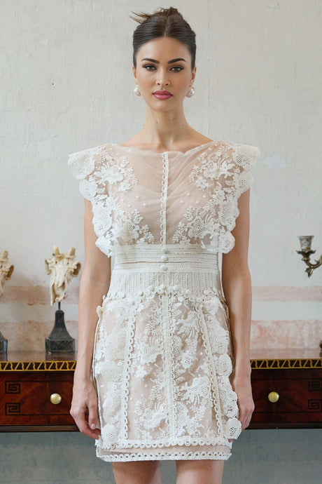 A white mini dress with floral embroidery and lace detailing named Maia
