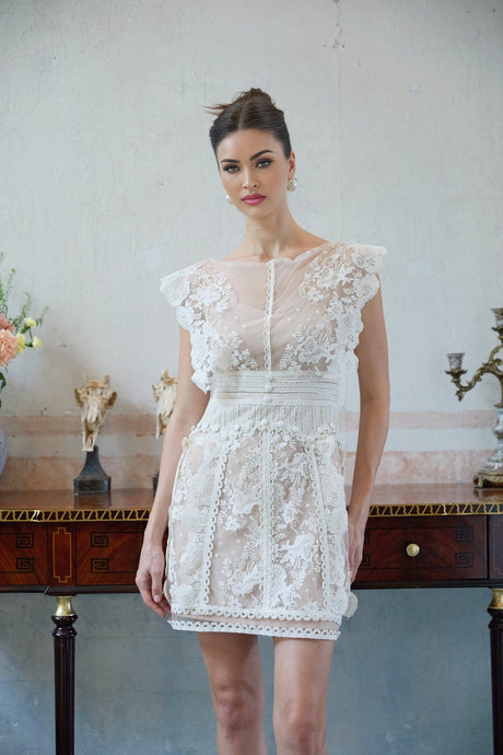 A white mini dress with floral embroidery and lace details featuring a short hemline and delicate design
