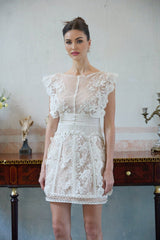 A white mini dress with floral embroidery and lace details featuring a short hemline and delicate feminine design
