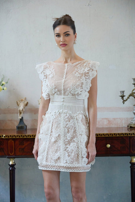 A white mini dress with floral embroidery and lace details featuring a short hemline and delicate feminine design